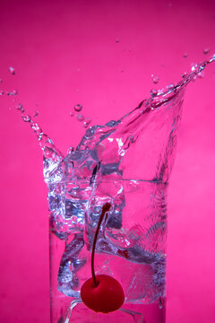 Water splash with cherry and ice on pink