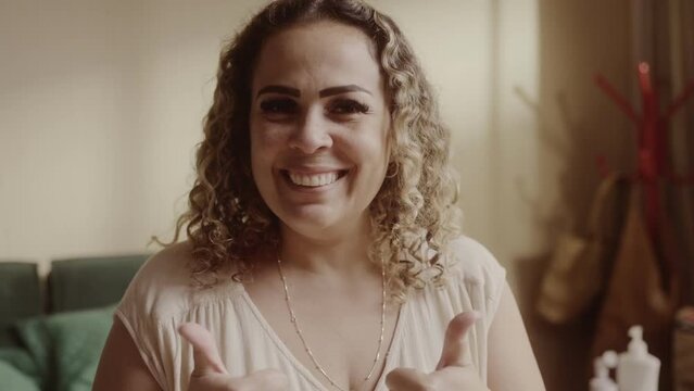 Mulher loira de cabelos cacheados sorrindo e fazendo sinal de positivo com as maos. Cinematico 4k.