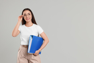 Happy woman with folder on light gray background, space for text