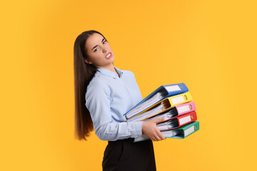 Disappointed woman with folders on orange background