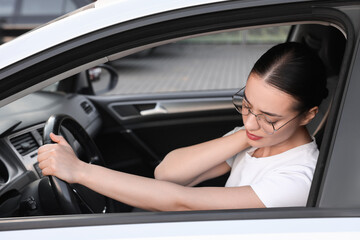 Young woman suffering from neck pain in her car