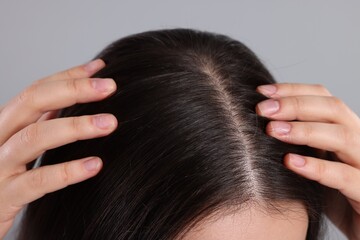 Fototapeta premium Woman examining her hair and scalp on grey background, closeup