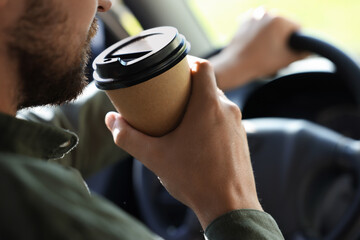 To-go drink. Man drinking coffee while driving his car, closeup