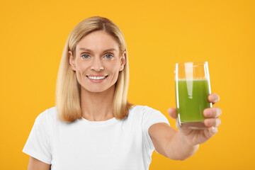 Happy woman with glass of fresh celery juice on orange background