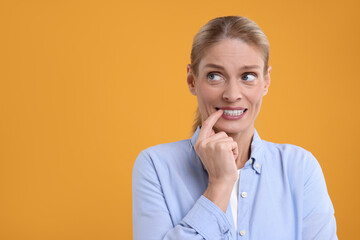Embarrassed woman on orange background. Space for text - obrazy, fototapety, plakaty