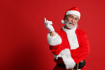 Fototapeta na wymiar Merry Christmas. Santa Claus posing on red background, space for text