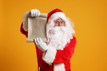 Merry Christmas. Santa Claus showing blank paper sheet on orange background