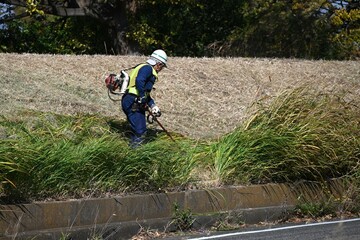A scene of mowing work on the river bank. Background material of the workplace of workers.