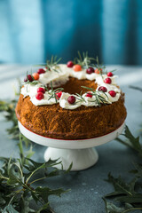 Christmas chocolate bundt cake. Traditional Christmas fruit cake with white glaze, cranberries and rosemary on dark backgroundChristmas decoration. Winter baking at Xmas or New Year. Copy space.