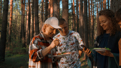 Adult group of friends camping and having a barbecue. Stock footage. Spending time outdoors in summer forest.