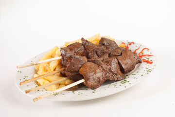 Peruvian Culinaria: A plate of anticuchos served generously, on a plate and with a white bottom.