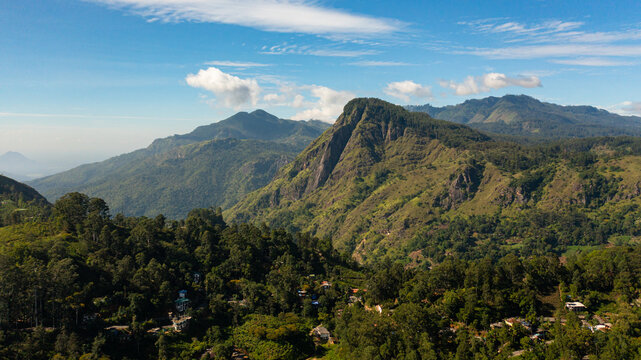 Aerial drone of Mountains covered with forest against a background of blue sky and clouds. Mountainous terrain in Sri Lanka.