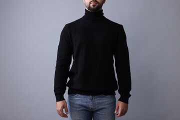 Man in stylish black sweater on grey background, closeup