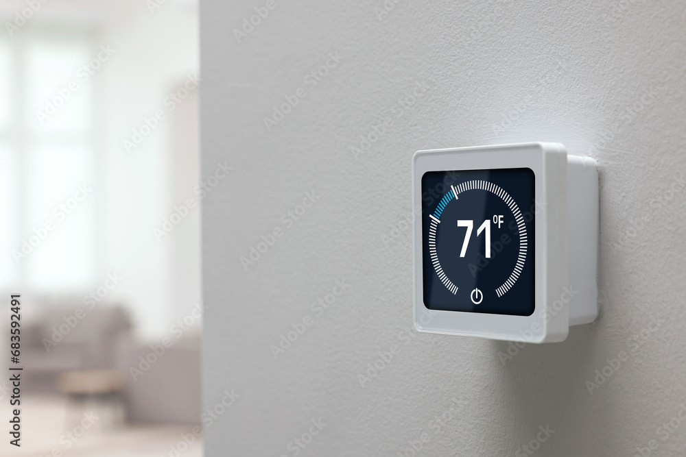 Poster thermostat displaying temperature in fahrenheit scale. smart home device on white wall, space for te