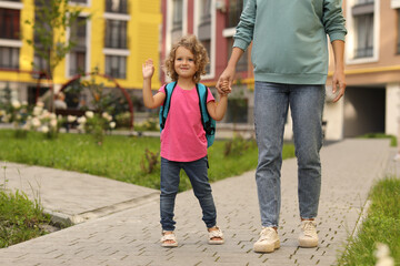 Woman and her little daughter on their way to kindergarten outdoors, closeup. Space for text