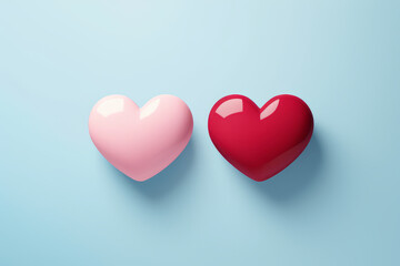Close up photo of two candy hearts, one pink and one red heart isolated on light blue background