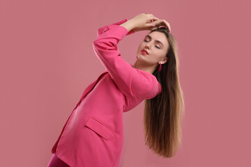 Fototapeta premium Beautiful young woman in pink clothes on color background
