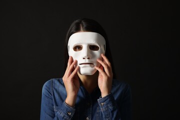 Multiple personality concept. Woman in mask on black background