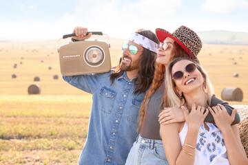 Happy hippie friends with radio receiver in field