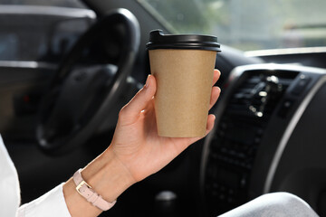 Coffee to go. Woman with paper cup of drink in car, closeup