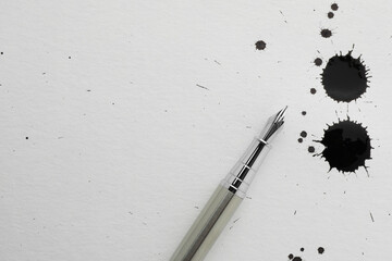 Stylish fountain pen on paper with drops of ink, top view. Space for text