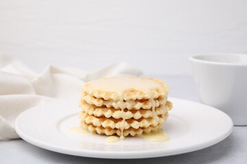 Tasty waffles with condensed milk on light grey table