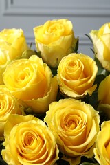 Beautiful bouquet of yellow roses near light wall, closeup