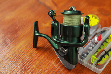 Fishing tackle. Spinning reel, lures and bait on wooden table, closeup. Space for text