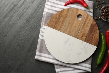 Cutting board, spices and kitchen towel on dark grey table, flat lay. Space for text