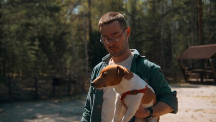 Man holds dog in hands in woods. Stock footage. Man holds Jack Russell terrier in arms. Man holds...