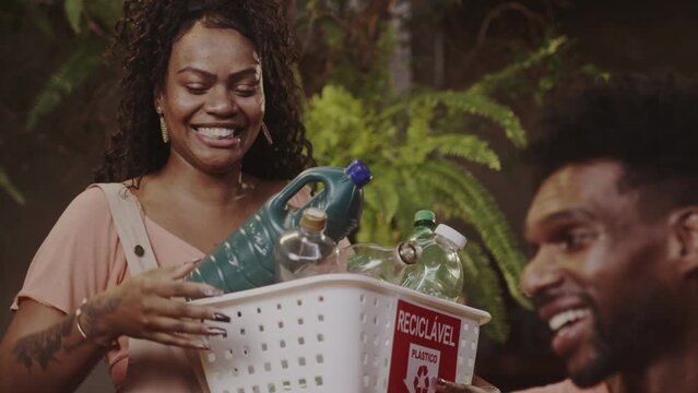Jovens felizes se cuprimentando apos joarem lixo reciclavel fora.