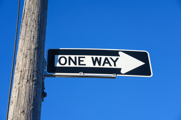 One way sign against a blue sky background