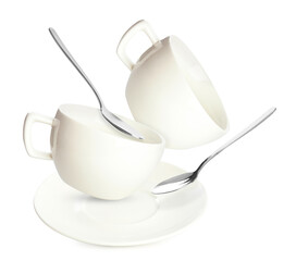 Clean saucer, spoons and cups falling on white background