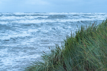 Sturmflut am Meer mit Wellen und Düne im Vordergrund