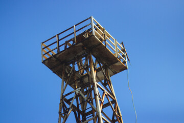 Old, rusty beach lifeguard tower against a clear blue sky