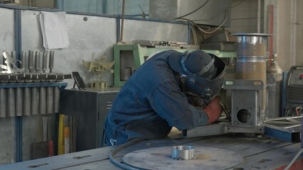 Welder in workshop repairs structure with sparks. Creative. Work of welder in industrial...