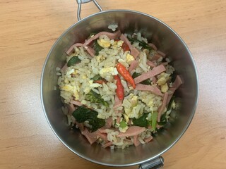 Ham and egg fried rice with fresh chilies on top in a stainless steel lunchbox.