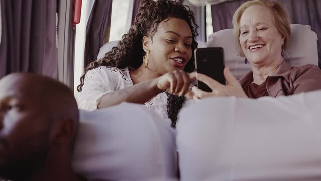 Mulher idosa mostrando algo em seu celular para uma mulher no onibus. Cinematico 4k.