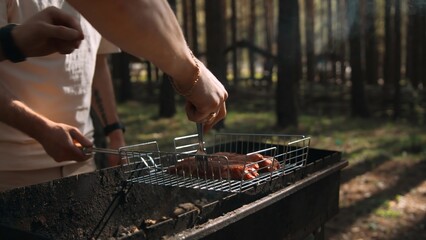 Close-up of men frying chicken on grill in forest. Stock footage. Delicious grilled chicken with...