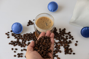 Male hand holding coffee beans Coffee mug with crema With coffee capsule elements on a white background