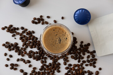 Coffee mug with crema with coffee capsule elements, coffee beans, on a white background.