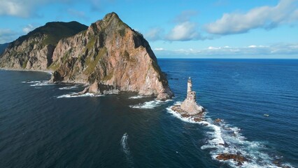 Top view of dramatic landscape of rocky island and lighthouse in sea. Clip. Cinematic fairy-tale...