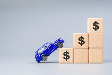 Toy car try to climb the high and steep wood blocks, with money icon, cost of purchasing a new car, maintenance, down payment, and installment, or insurance