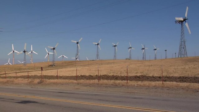 Wind turbines working on rolling hills by the road in Altamont Pass wind farm in California, USA