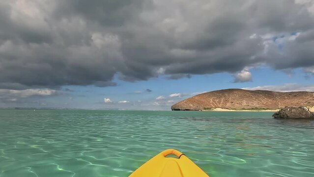 Landscape of Balandra beach from a yellow kayak, with the view of crystal water and dark clouds