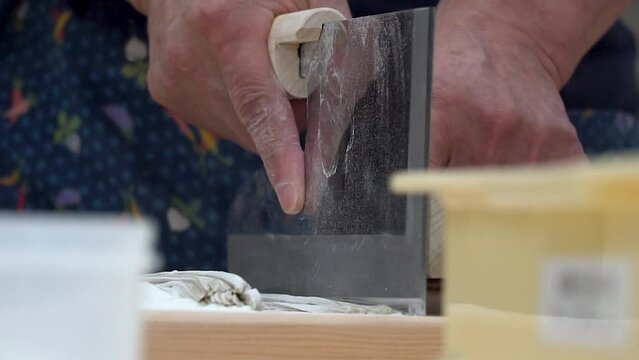 The Art of Soba: A close-up of a skilled hand meticulously slicing fresh soba noodles with a traditional Japanese knife, highlighting the intricate details and craftsmanship of this culinary art. 