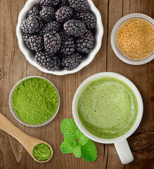 Matcha latte at a cafe with blackberries pistachios nuts and berries on flat wood background
