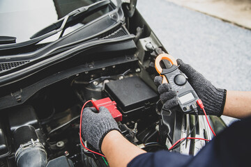 Close-up hand auto mechanic using meter to check car battery fail problem to change repairing and...
