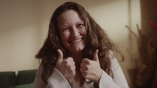 Mulher jovem de cabelos ondulados sorrindo e fazendo sinal de positivo com as maos. Cinematico 4k.