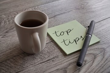 Closeup image of cup of coffee, pen and sticky note with text TOP TIPS.